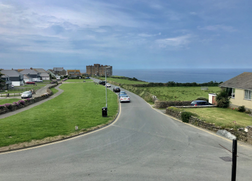 The lane at Tintagel sloping down towards the Atlantic, with green headland and open sea beyond