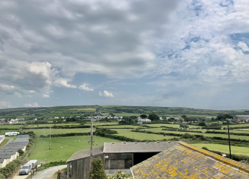 Rolling countryside and distant village rooftops seen from an upper window at Pendrin