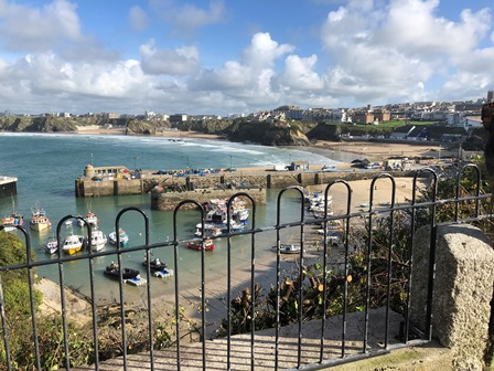 A Cornish harbour and its wide town beach seen from the cliff steps above